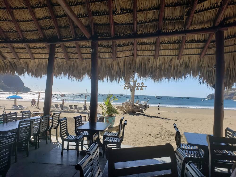 View out to the ocean under the palapa or rancho of Restaurante El Timón