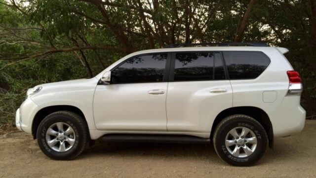 White Surf Bus shuttle van parked in San Juan del Sur with surfboards on roof rack