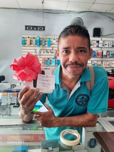 Technician repairing mobile phones at Tel Cell San Juan Del Sur with accessories displayed on the counter