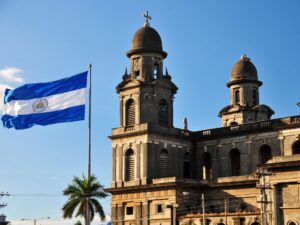 Visas de inmigración de Nicaragua, residencia y lo que los expatriados necesitan saber Imagen de la bandera nicaragüense y el edificio de inmigración en Managua
