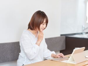 Lista de verificación de medicamentos de emergencia para la tiroides: Exámenes de sangre para la tiroides Por qué "normal" no es suficiente Mujer mirando en su ordenador los resultados de sus análisis de sangre, luciendo pensativa